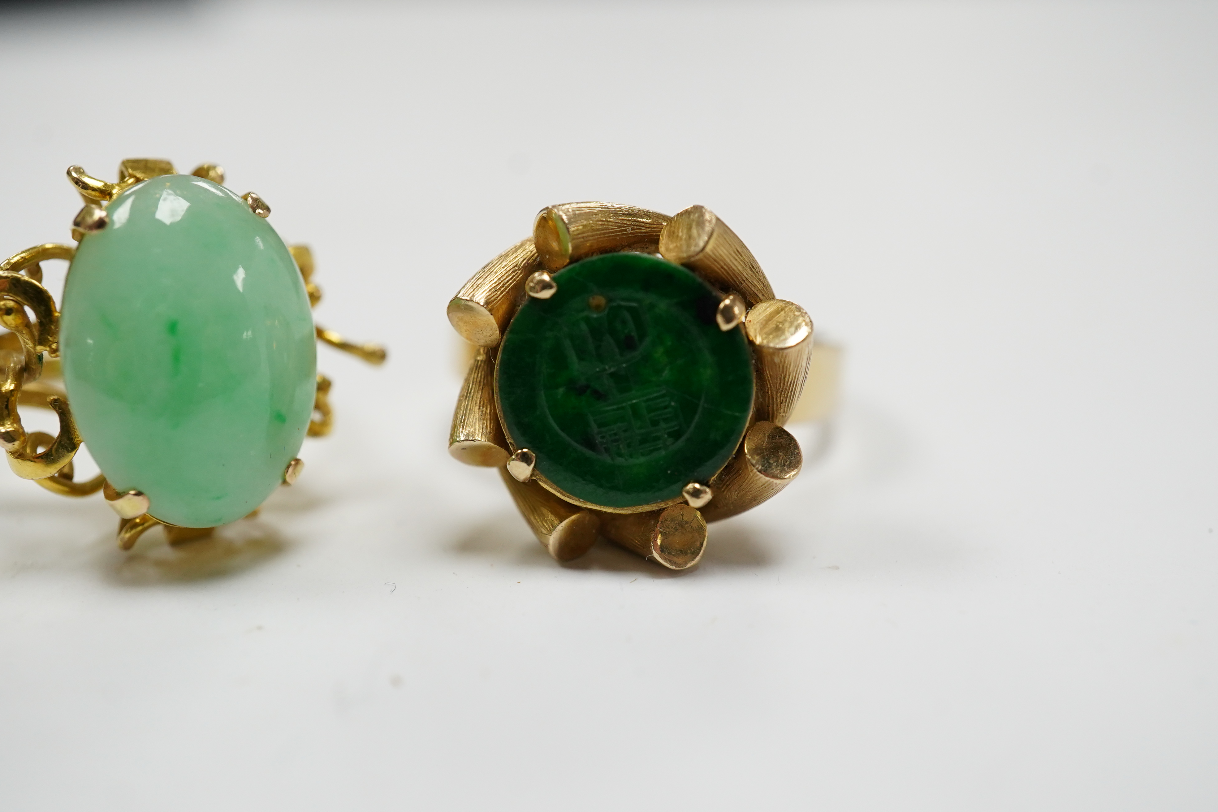 A Chinese 14k and single stone oval cabochon jadeite set ring, size P and a similar 14k and spinach green jade mounted ring, size O, gross weight 11.1 grams. Condition - fair to good